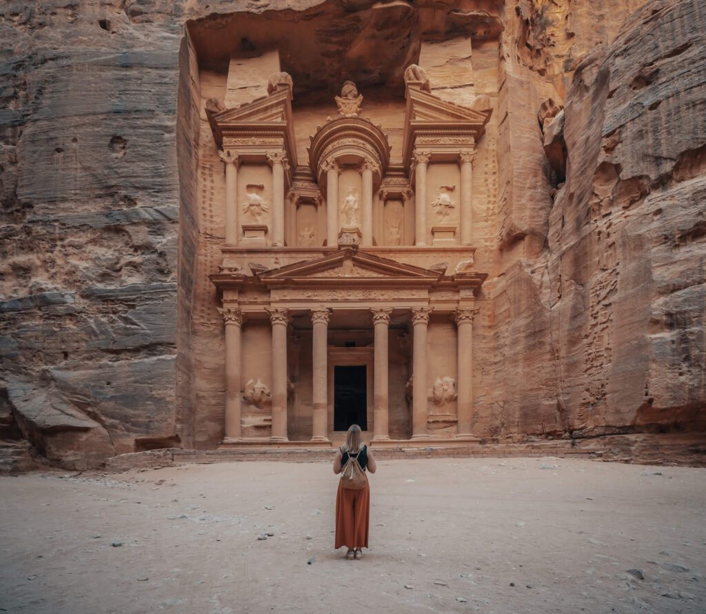 Female in a long orange skirt standing in front of the historic Petra Wadi in Jordan